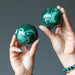 hands holding a malachite sphere