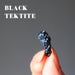 fingers holding black tektite