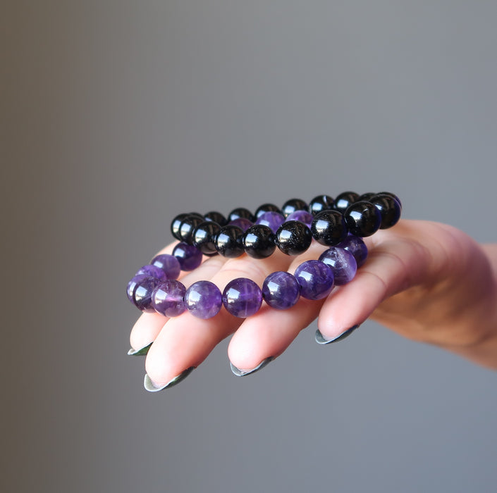 female hand with black tourmaline and amethyst bracelet set in palm