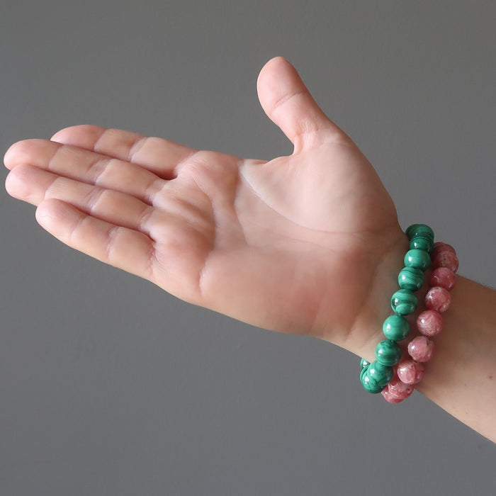 hand wearing pink rhodochrosite and green malachite stretch bracelets