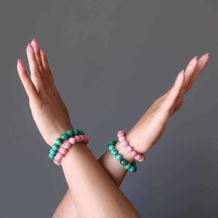 crossed hands wearing pink rhodochrosite and green malachite stretch bracelets