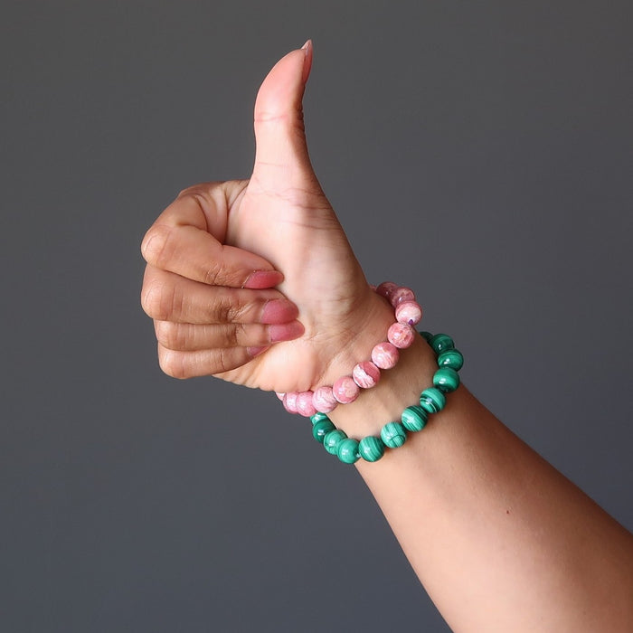 hand wearing pink rhodochrosite and green malachite stretch bracelets