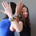 two females back to back with hands up modeling tourmaline quartz and serpentine bracelet set