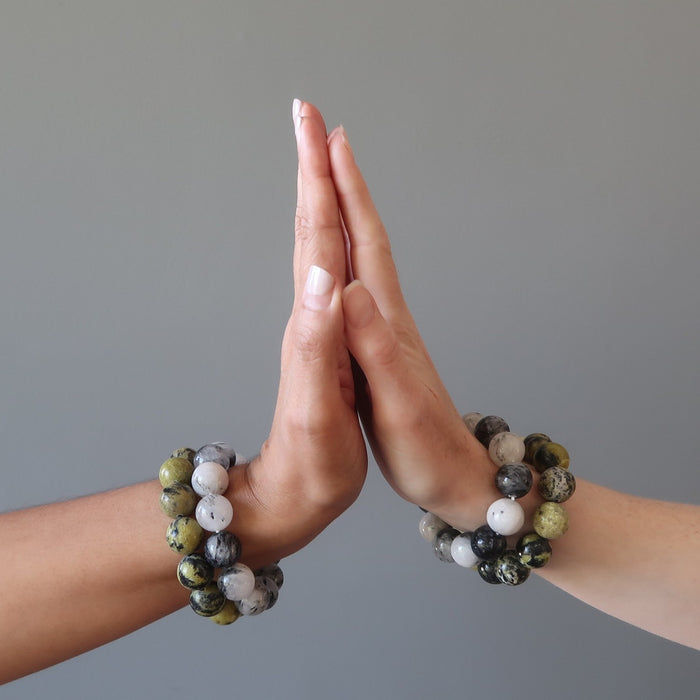 female hands palm to palm both modeling tourmaline quartz and serpentine bracelet sets