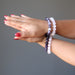 female hands clasped together both modeling amethyst and rose quartz bracelet sets