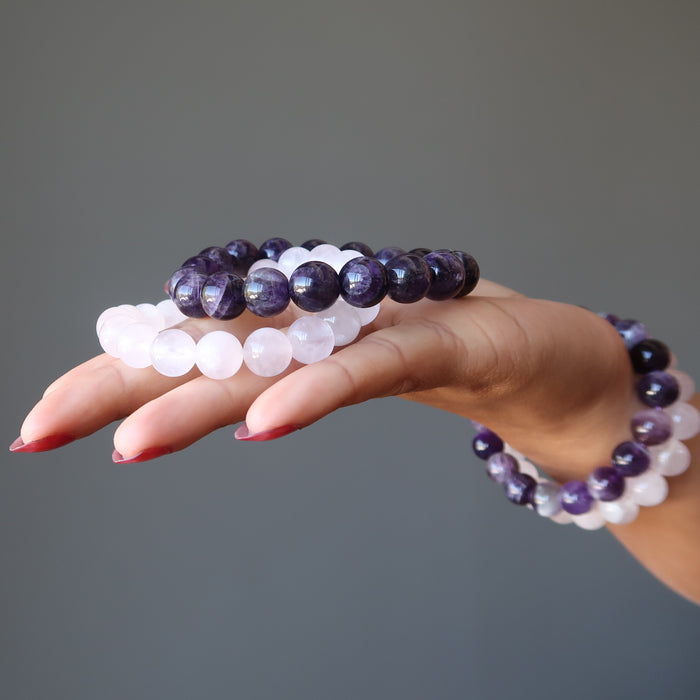 hand holding and wearing amethyst and rose quartz bracelet sets