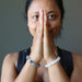 Sheila Satin of Satin Crystals has her hands in prayer to display rainbow fluorite bracelet on one arm and white selenite bracelet on the other