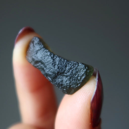 hand holding natural green moldavite crystal