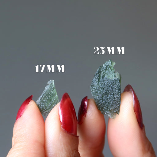 hands holding two moldavite to show size difference