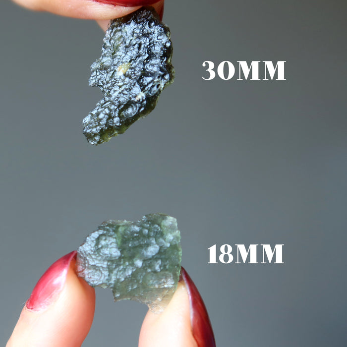 hands holding real moldavite showing size difference