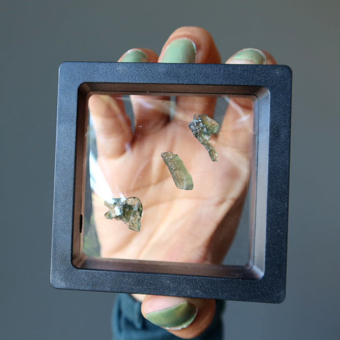 rough green moldavite gemstones in display case