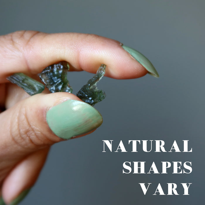 hand holding three rough green moldavite gemstones showing natural shapes vary