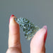 hand holding green raw moldavite hedgehog tektite