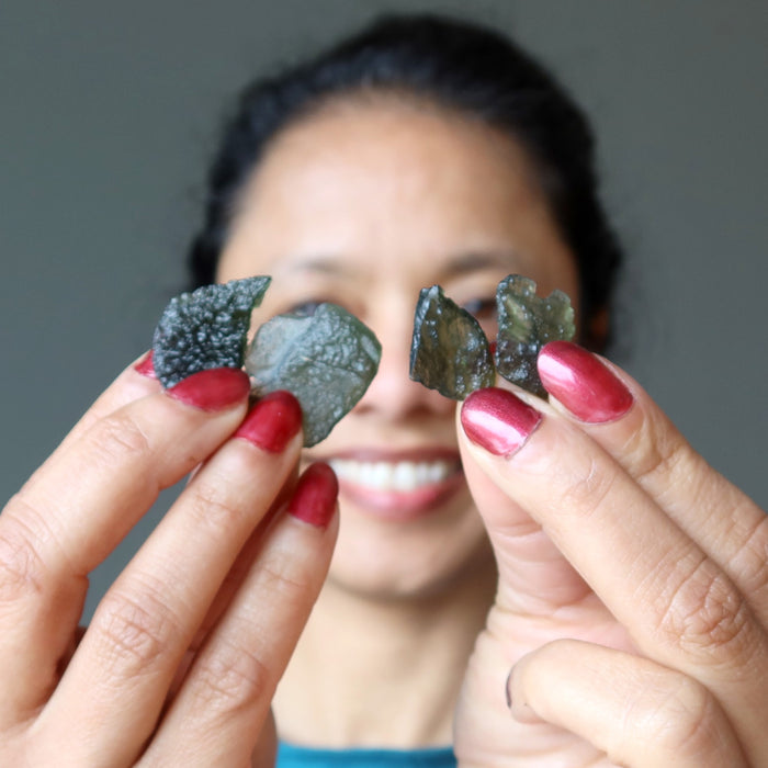 female holding two pairs of moldavite stones