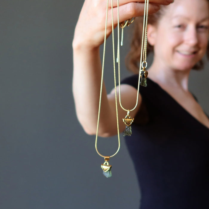 female holding three gold moldavite necklaces