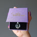 female holding moldavite tumbled sterling silver cage necklace in purple satin crystals box