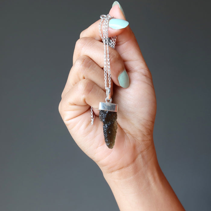 hand holding moldavite pendant necklace