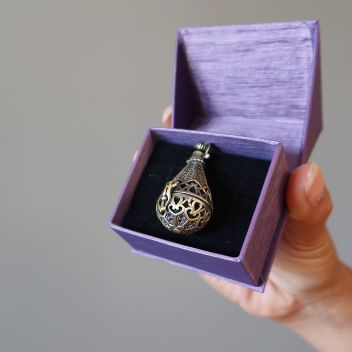 hand holding moldavite locket necklace in purple gift box