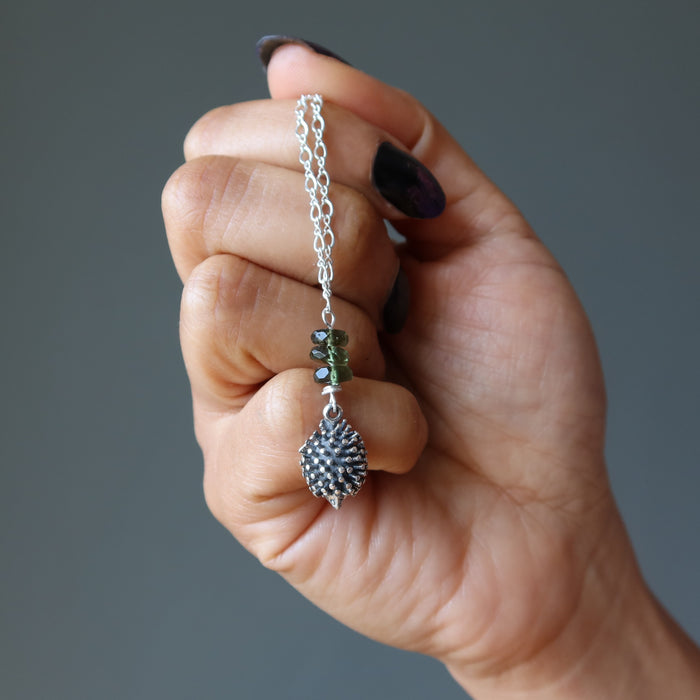 hand holding sterling silver hedgehog moldavite necklace