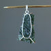 hand holding large raw moldavite in sterling silver pendant showing back