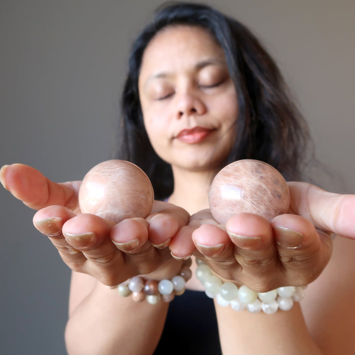 sheila of satin crystals meditating with two peach moonstone spheres