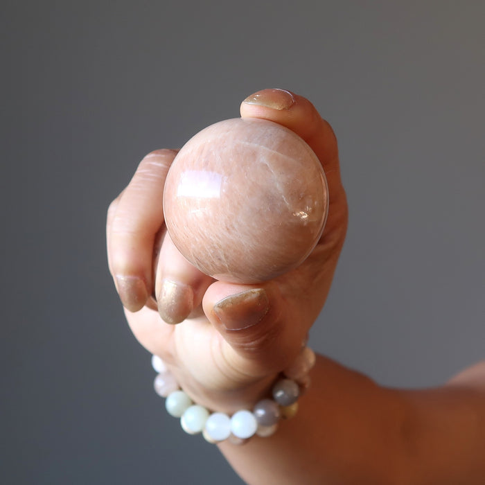hand holding a peach moonstone sphere