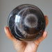 hand holding black moonstone sphere with bullseye formation