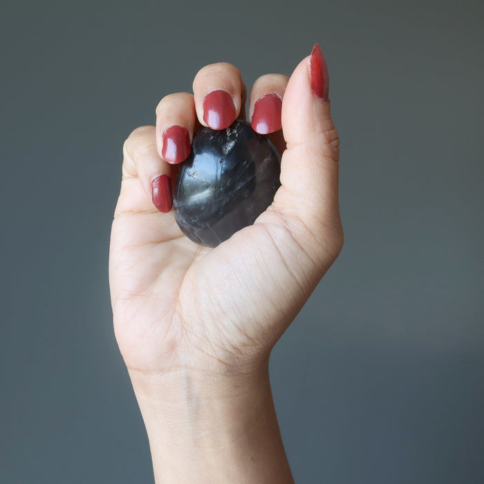 hand holding black moonstone palm stone