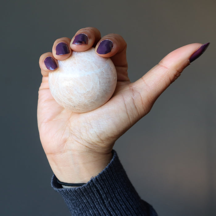 hand holding cream moonstone sphere