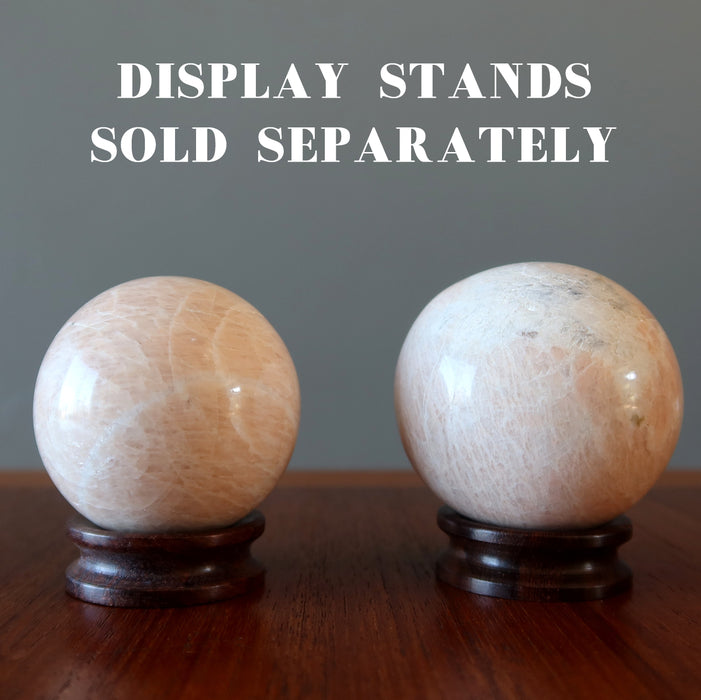 two cream moonstone spheres on wood stands