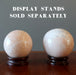 two cream moonstone spheres on wood stands