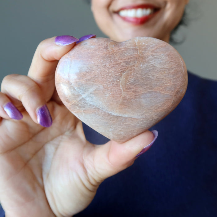 woman holding peach moonstone heart