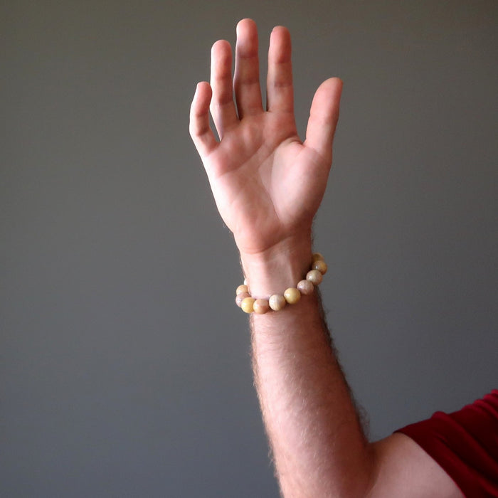 man's hand wearing yellow peach moonstone round stretch bracelet