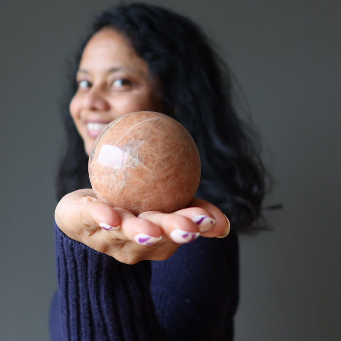 sheila of satin crystals holding a peach moonstone sphere