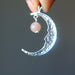 hand holding a sterling silver smiling crescent moon pendant hanging with peach moonstone showing the back