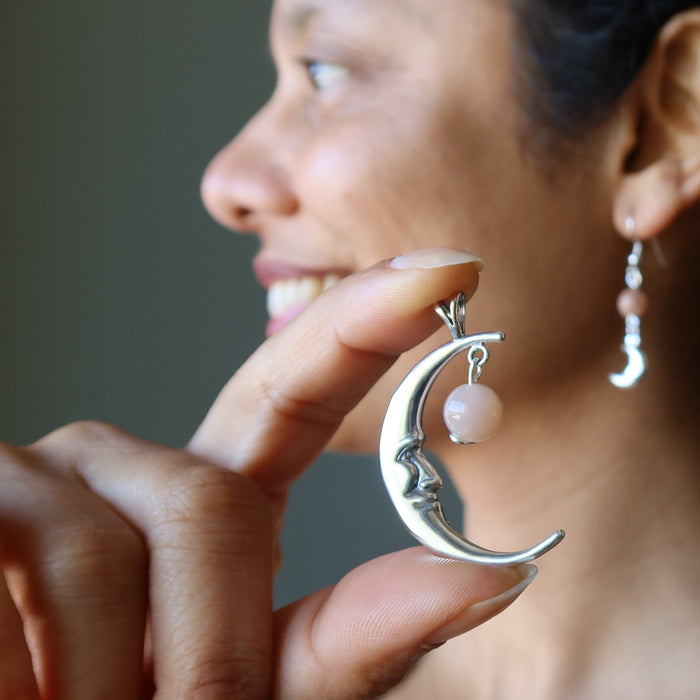 hand holding a sterling silver smiling crescent moon pendant hanging with peach moonstone
