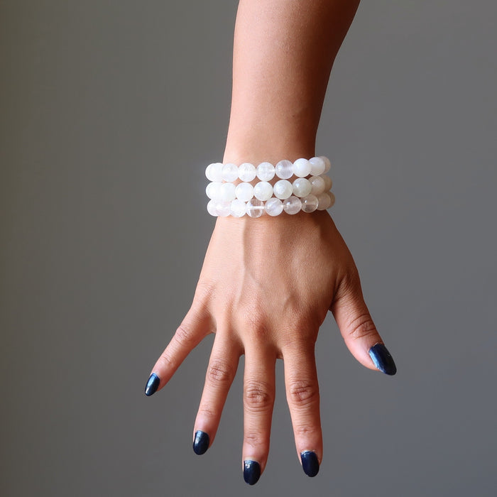hand wearing white rainbow moonstone beaded stretch bracelets