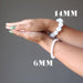 hands clasped wearing 6mm and 14mm rainbow moonstone bracelet on each wrist