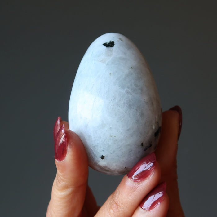 hand holding a moonstone tourmaline egg
