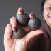 sheila of satin crystals holding out hand holding three brown moqui marble stones