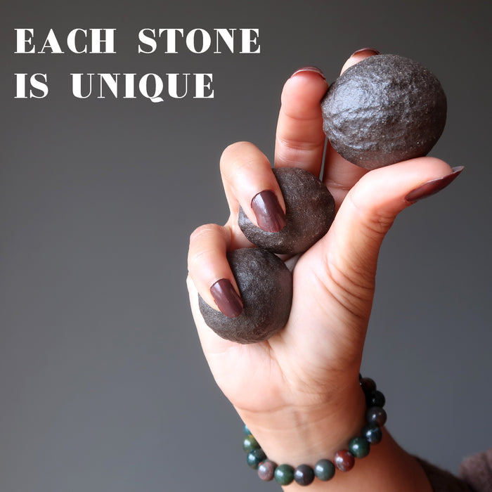 hand holding three brown moqui marble stones showing each is unique