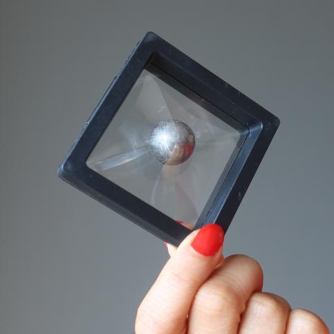 holding a meteotire ball in Black Floating Display Case