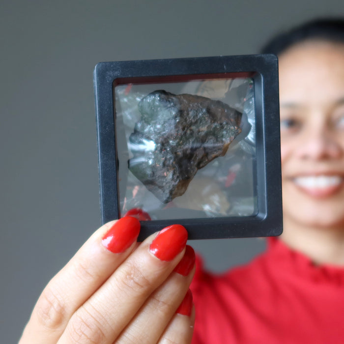 sheila of satin crystals holding brown rocky nantan meteorite in zero gravity case