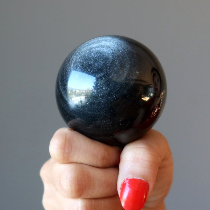 hand holding silver sheen obsidian sphere