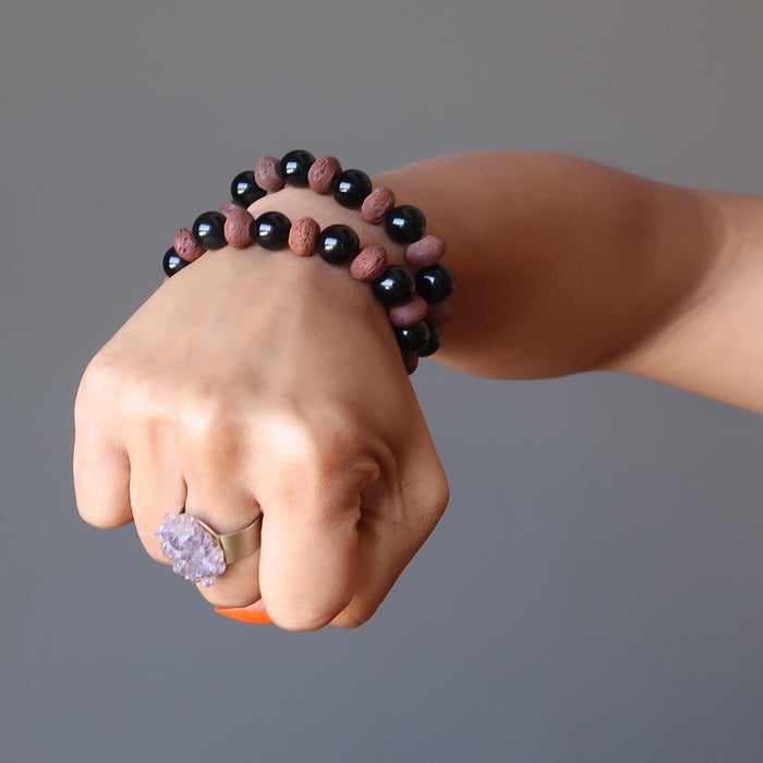 woman's hand making a fist wearing 2 obsidian lava bracelets