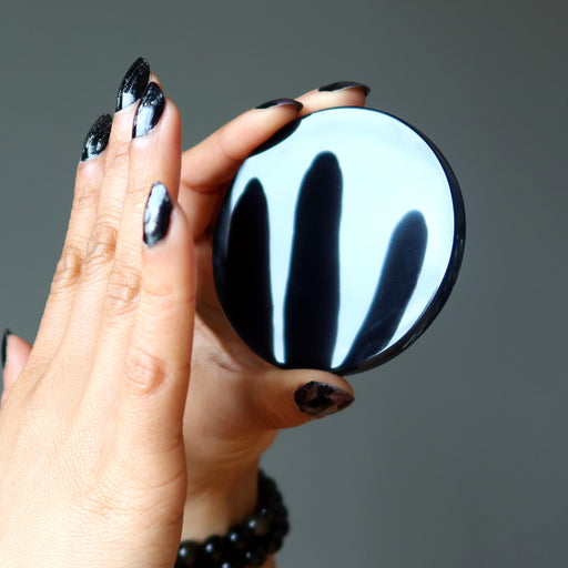 black obsidian circle mirror stone reflecting fingers held in front of it