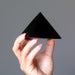 hand holding black obsidian pyramid
