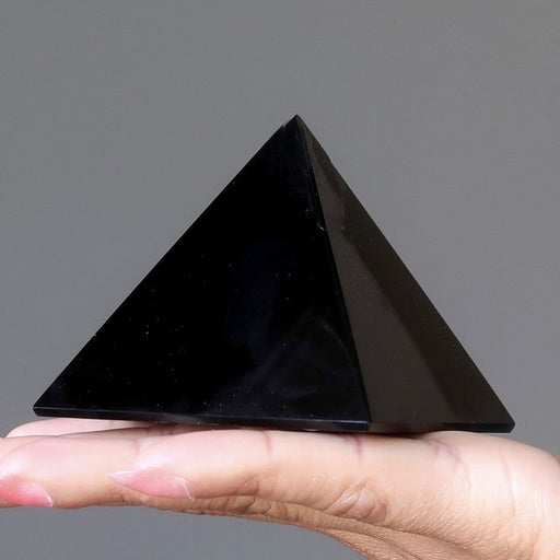 black obsidian pyramid on palm of hand