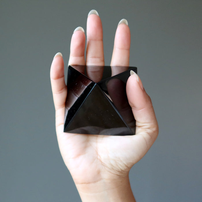 black obsidian pyramid in palm of hand