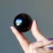 hand holding black obsidian sphere